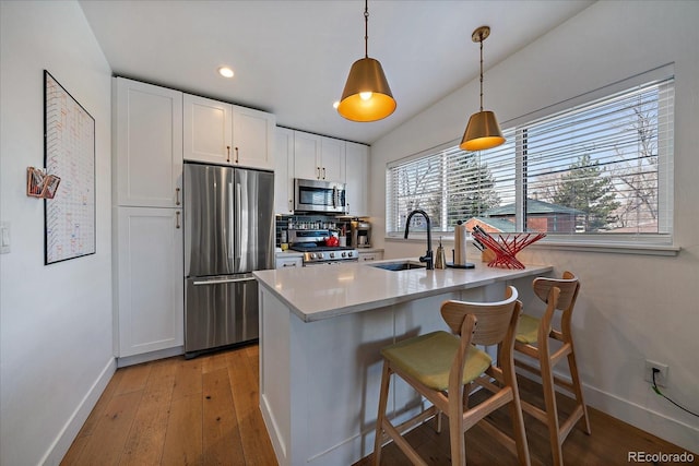 kitchen featuring white cabinetry, baseboards, stainless steel appliances, and a sink
