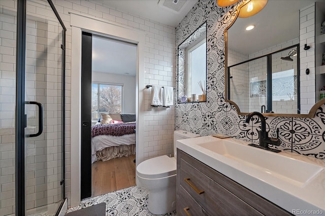 full bath with ensuite bathroom, a stall shower, vanity, tile walls, and visible vents