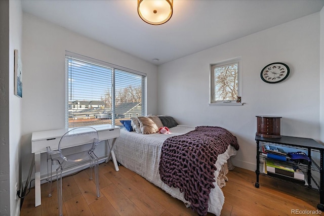 bedroom featuring light wood finished floors, baseboards, and multiple windows