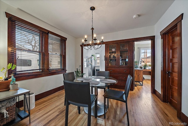 dining space with a chandelier, light wood finished floors, and baseboards