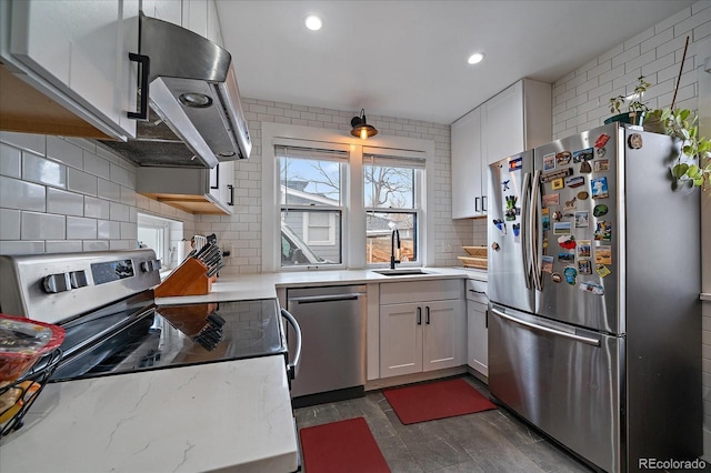 kitchen featuring white cabinets, a sink, tasteful backsplash, recessed lighting, and appliances with stainless steel finishes