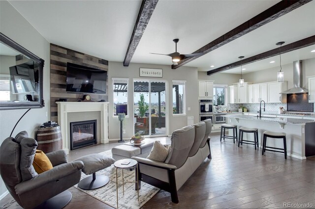 living room with sink, hardwood / wood-style floors, beam ceiling, and ceiling fan