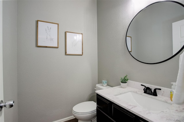 bathroom with toilet, baseboards, and vanity