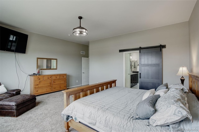 carpeted bedroom with visible vents, ensuite bathroom, and a barn door