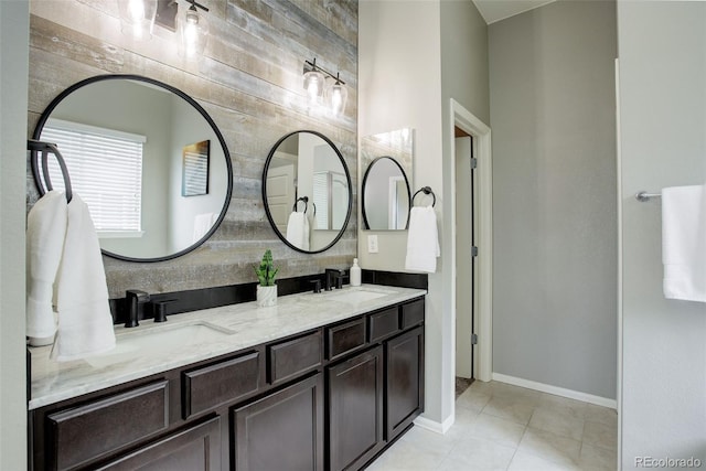 bathroom featuring double vanity, tile patterned flooring, a sink, and baseboards