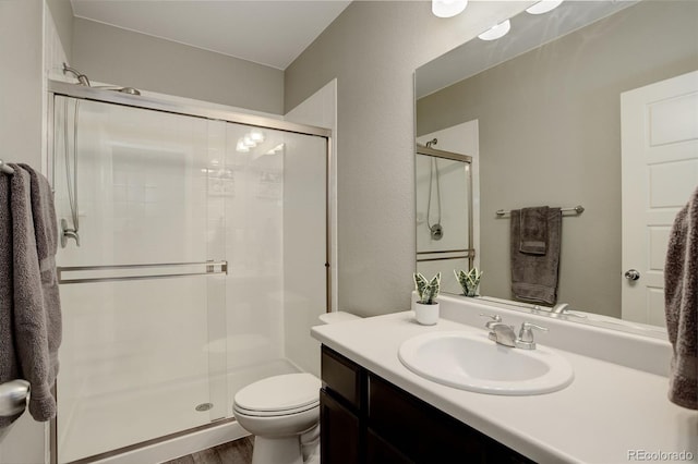 full bathroom featuring toilet, a stall shower, and vanity