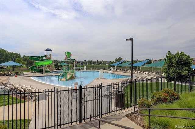 pool featuring fence, a water play area, a water slide, and a patio