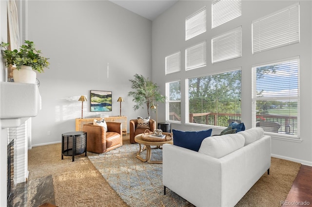 9453 Lark Sparrow Dr, Highlands Ranch, CO 80126 - living room featuring baseboards, a towering ceiling, a brick fireplace, and wood finished floors