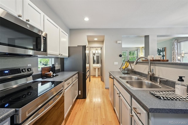 2813 Central Park Blvd, Denver, CO 80238 - kitchen with appliances with stainless steel finishes, a sink, light wood-style floors, dark countertops, and white cabinetry