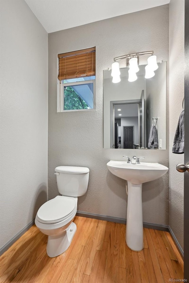 2813 Central Park Blvd, Denver, CO 80238 - bathroom featuring toilet, wood finished floors, a sink, a textured wall, and baseboards