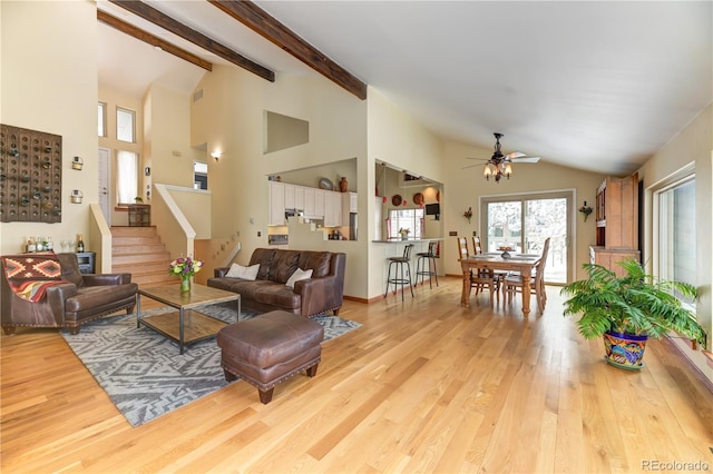 living room with ceiling fan, wood finished floors, visible vents, stairway, and beam ceiling