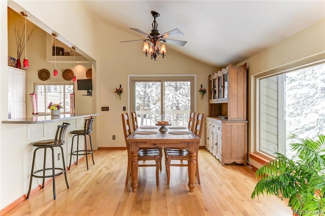 dining area featuring light wood finished floors, ceiling fan, baseboards, and vaulted ceiling