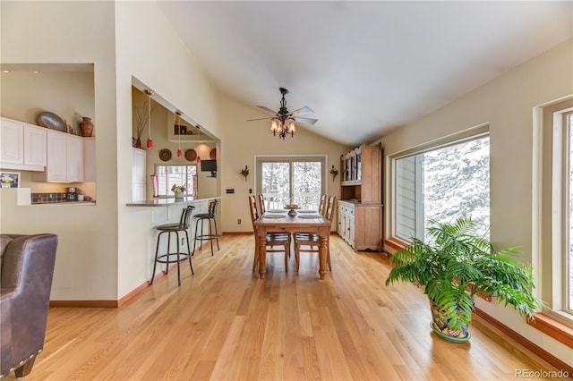 dining room with vaulted ceiling, baseboards, a ceiling fan, and light wood-style floors