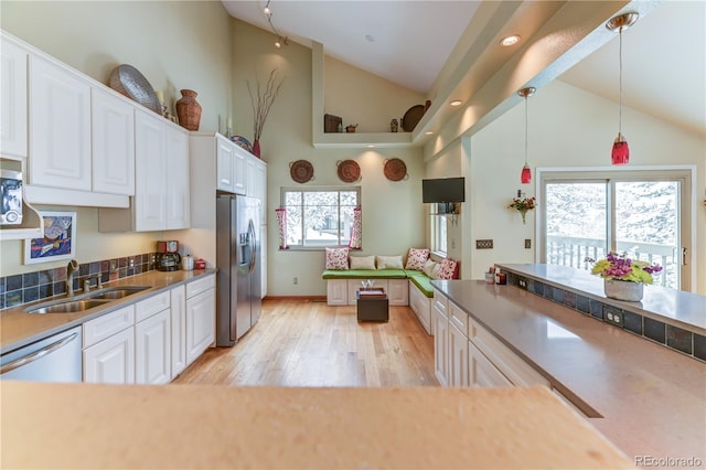 kitchen with light wood finished floors, stainless steel fridge, dishwashing machine, white cabinetry, and a sink