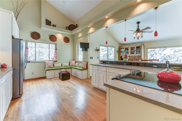 kitchen with light wood-style floors, black electric cooktop, a wealth of natural light, and freestanding refrigerator