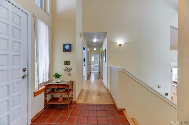 interior space featuring baseboards, dark tile patterned floors, a towering ceiling, and a healthy amount of sunlight