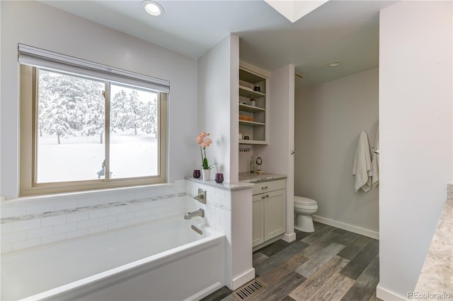 full bath with baseboards, toilet, wood finished floors, vanity, and a bath