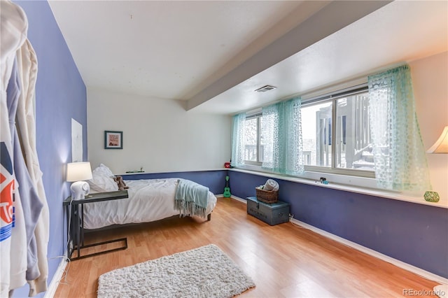 bedroom featuring visible vents, baseboards, and wood finished floors