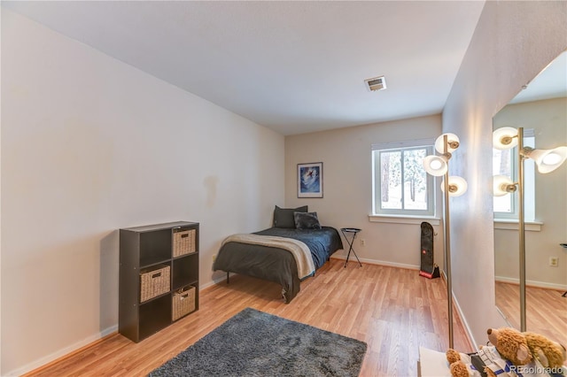 bedroom with light wood-style flooring, visible vents, and baseboards