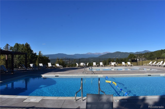 community pool with a mountain view, a patio, and fence