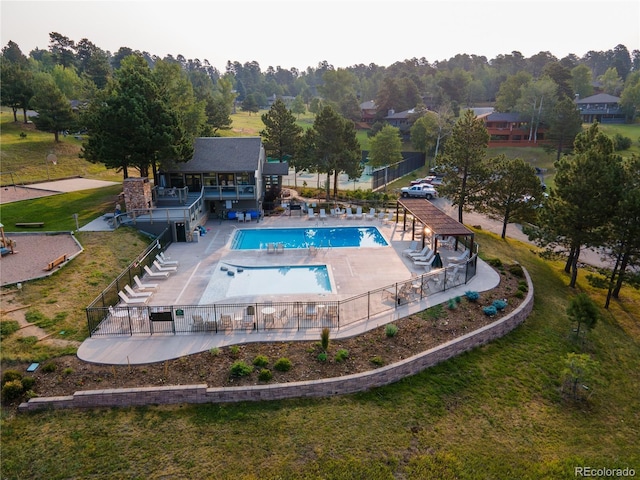 community pool with a patio area and fence