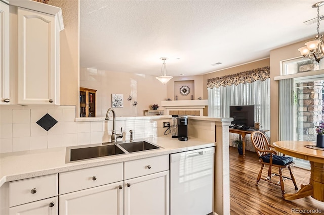 kitchen featuring wood finished floors, white dishwasher, a sink, light countertops, and backsplash