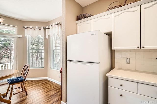 kitchen with white cabinets, backsplash, wood finished floors, and freestanding refrigerator