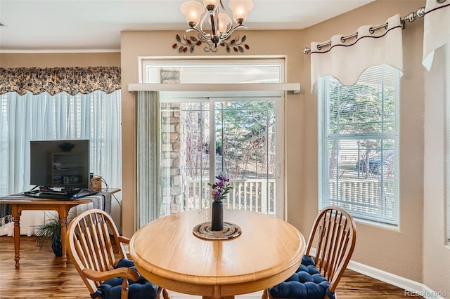 dining space with a notable chandelier, wood finished floors, and baseboards