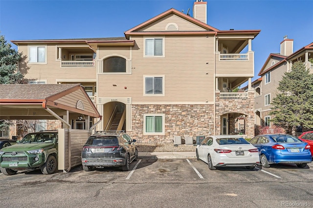 view of building exterior with stairway and uncovered parking