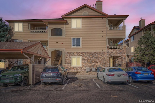 view of front of property with stairway, uncovered parking, and a chimney