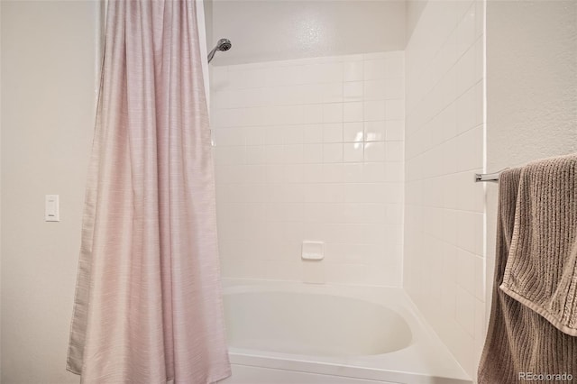 bathroom featuring a textured wall and shower / bath combo