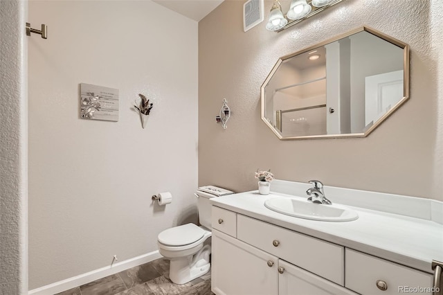 bathroom featuring vanity, baseboards, visible vents, walk in shower, and toilet