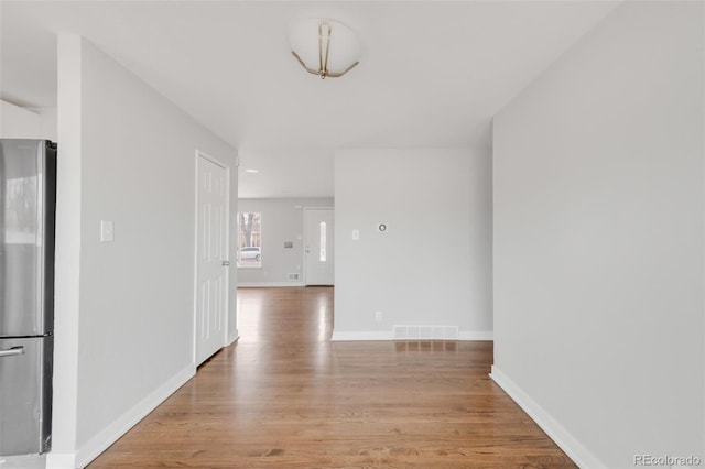 interior space featuring light wood-type flooring, visible vents, and baseboards