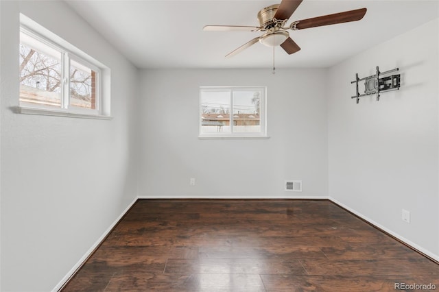 unfurnished room featuring baseboards, visible vents, dark wood finished floors, and a ceiling fan