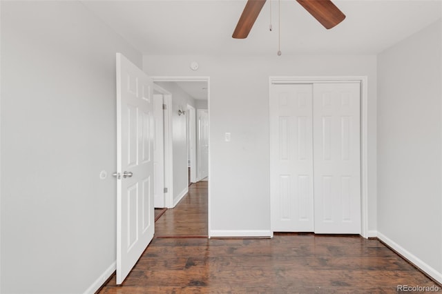 unfurnished bedroom featuring a closet, dark wood finished floors, baseboards, and ceiling fan