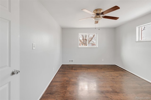 spare room featuring a ceiling fan, baseboards, visible vents, and dark wood-style flooring