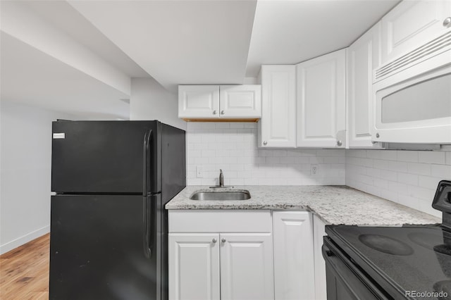 kitchen featuring light stone counters, a sink, white cabinetry, light wood-style floors, and black appliances