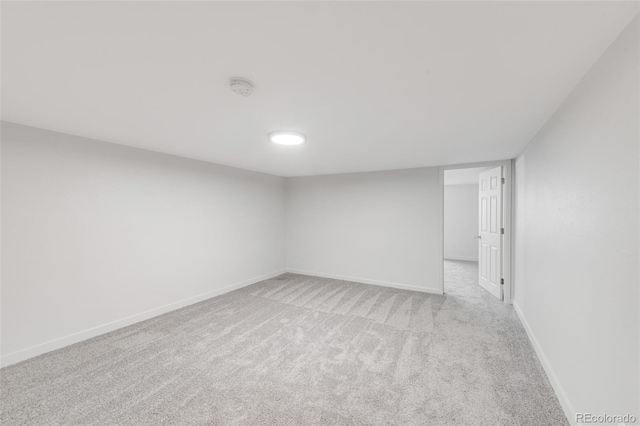 spare room with baseboards and light colored carpet