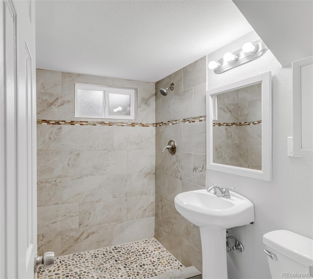 full bathroom featuring a textured ceiling, a stall shower, and toilet