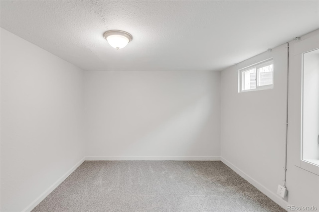 empty room featuring a textured ceiling, carpet floors, and baseboards