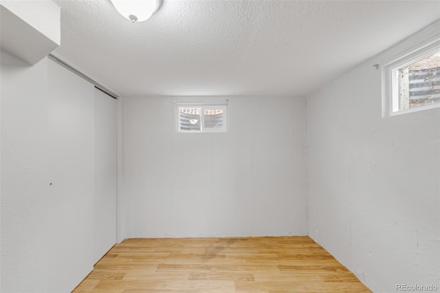 below grade area featuring light wood-type flooring and a textured ceiling