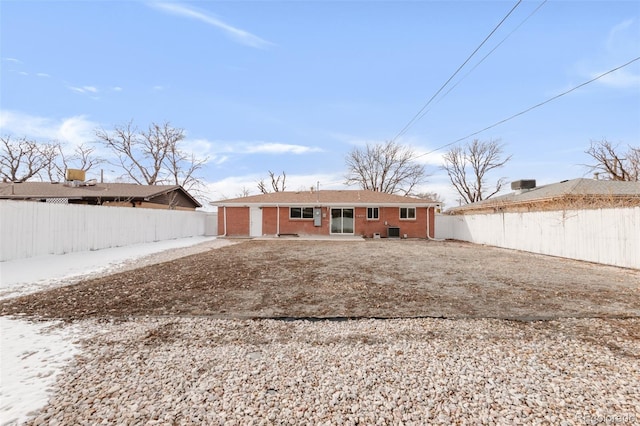 rear view of property featuring brick siding, cooling unit, and a fenced backyard