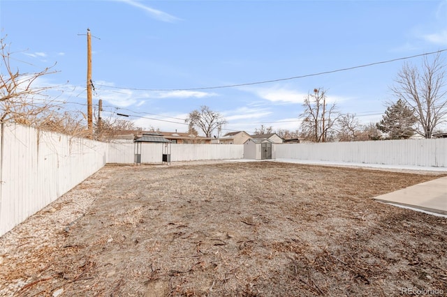 view of yard featuring a fenced backyard, a storage unit, and an outdoor structure