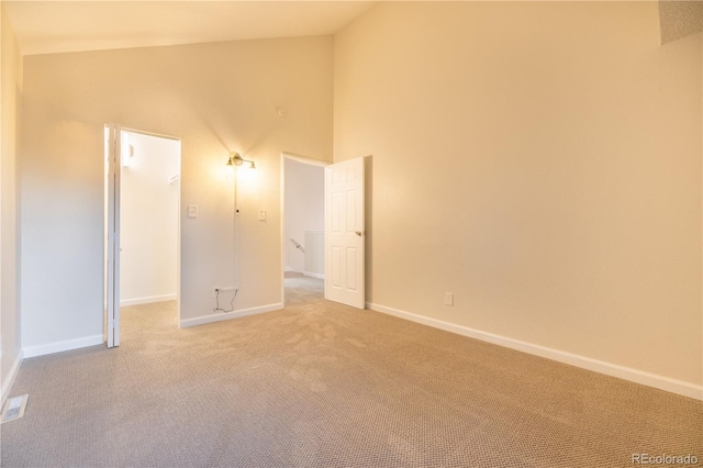 carpeted empty room with high vaulted ceiling