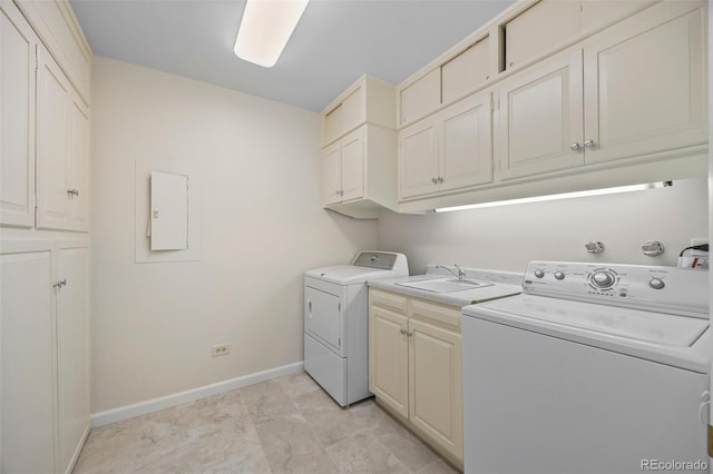 clothes washing area with cabinet space, washer and dryer, baseboards, and a sink