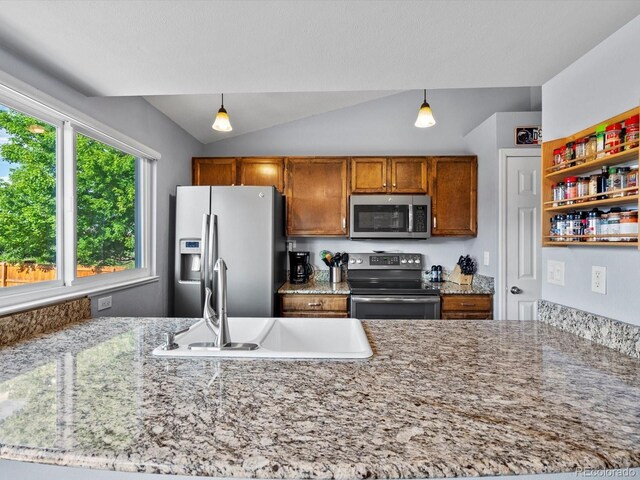 11877 W Bowles Cir, Littleton, CO 80127 - kitchen featuring appliances with stainless steel finishes, decorative light fixtures, lofted ceiling, brown cabinetry, and light stone counters