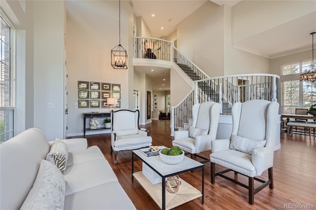 living room with dark wood-type flooring, a healthy amount of sunlight, an inviting chandelier, and a towering ceiling