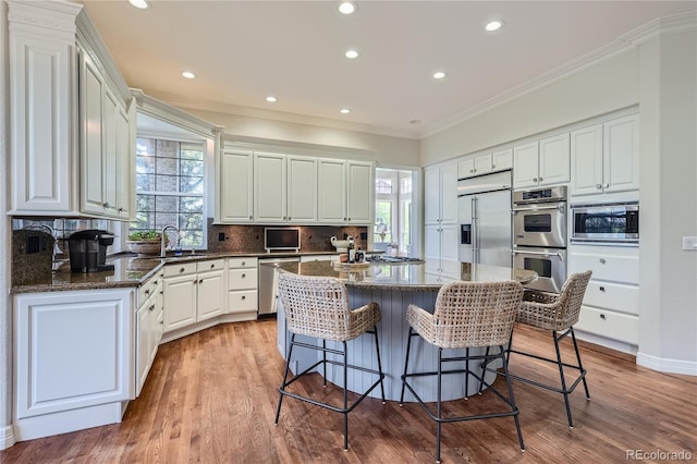 kitchen with a wealth of natural light, built in appliances, light hardwood / wood-style flooring, and a center island