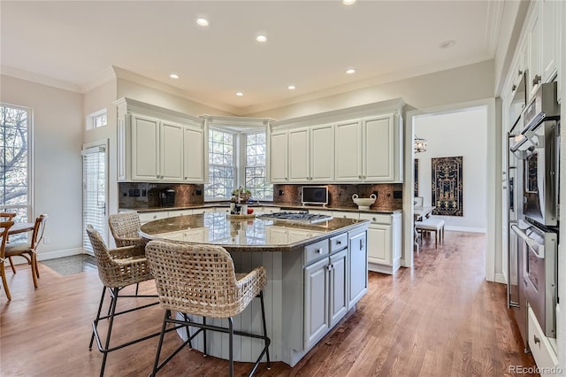 kitchen featuring a wealth of natural light, tasteful backsplash, a center island, and dark stone counters