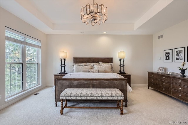 bedroom with a chandelier, light colored carpet, multiple windows, and a tray ceiling